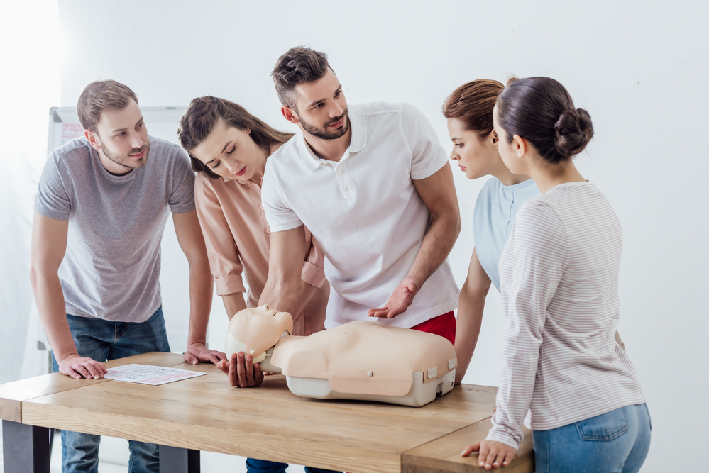 Gruppe bei der 16h Erste-Hilfe-Grundausbildung übt Herzdruckmassage an einer Trainingspuppe